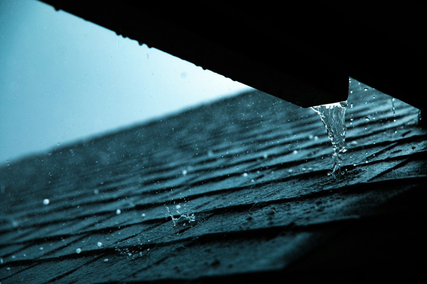 Rainwater sheeting off the edge of a roof during a downpour
