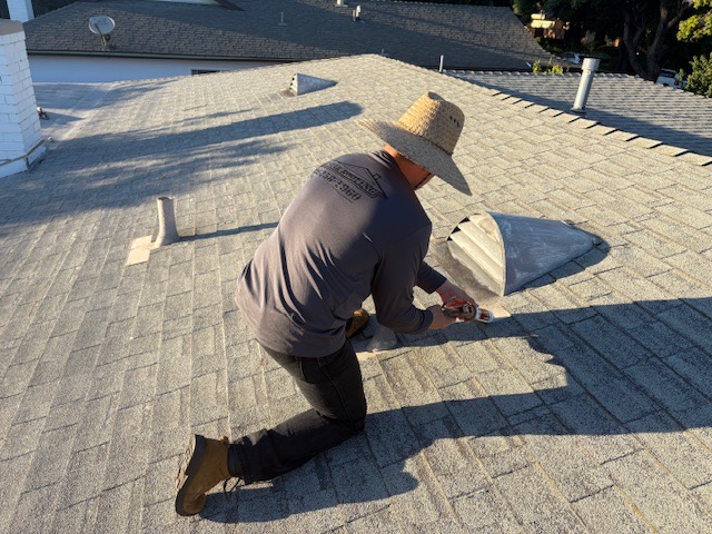 An All Star Roofing crew member in a branded company shirt kneeling on a shingle roof, fitting flashing during a repair